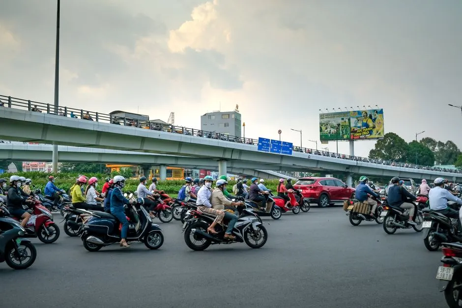 A bustling city intersection filled with motorbikes under an overpass, capturing urban transportation.