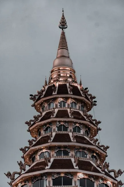 Vertical shot of an intricate Buddhist pagoda with ornate designs against a gray sky." loading="eager" fetchpriority="high